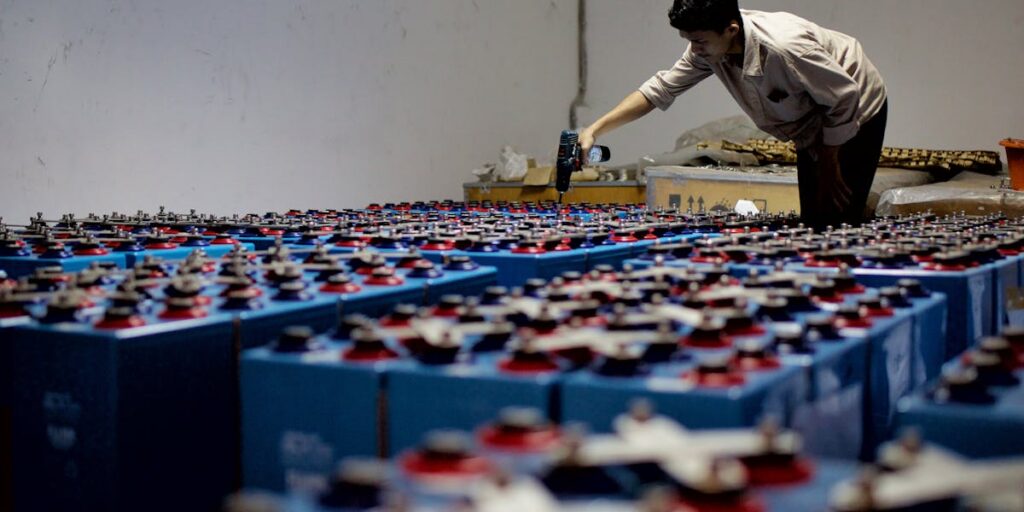 A worker inspecting used batteries in a warehouse